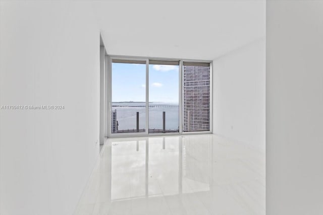 unfurnished room featuring a water view, tile patterned floors, and floor to ceiling windows