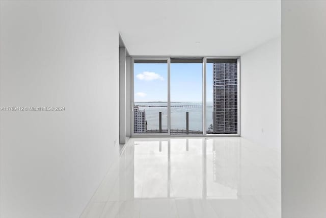 spare room featuring a water view and a wall of windows