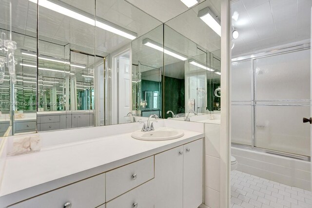 full bathroom featuring tile patterned flooring, vanity, combined bath / shower with glass door, and toilet