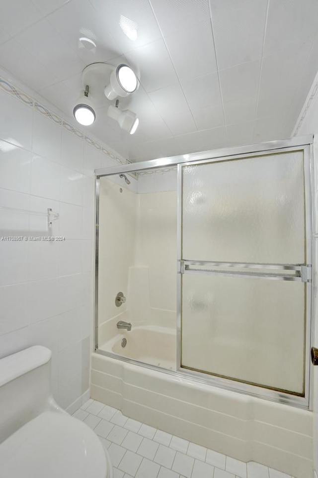 bathroom with shower / bath combination with glass door, tile patterned flooring, and toilet