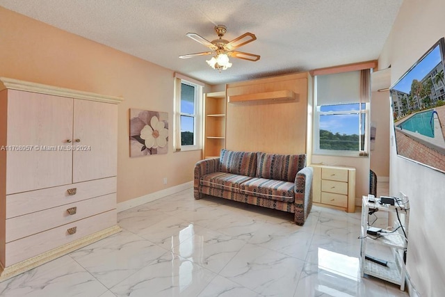 living room with a wall unit AC, ceiling fan, and a textured ceiling