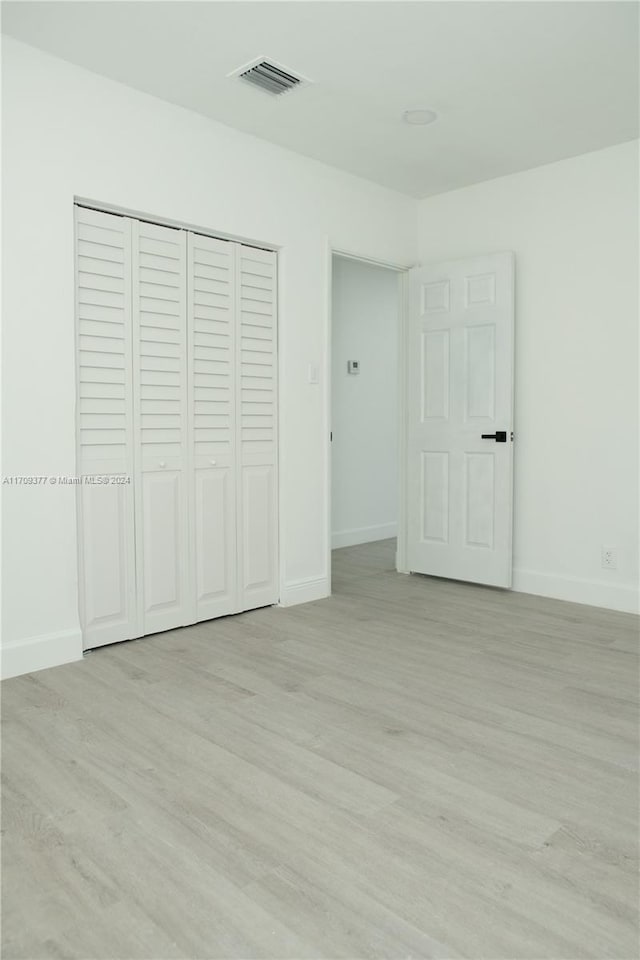 unfurnished bedroom with light wood-type flooring and a closet