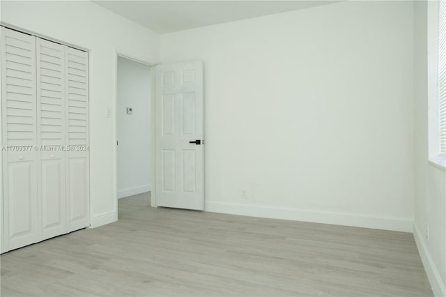 unfurnished bedroom with a closet and light hardwood / wood-style floors