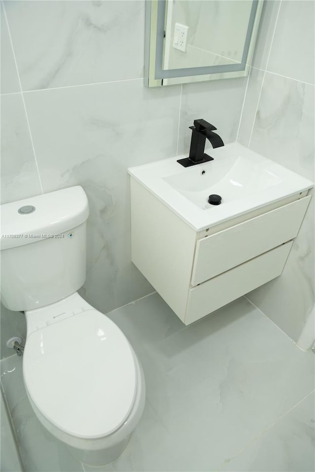 bathroom featuring vanity, toilet, and tile walls