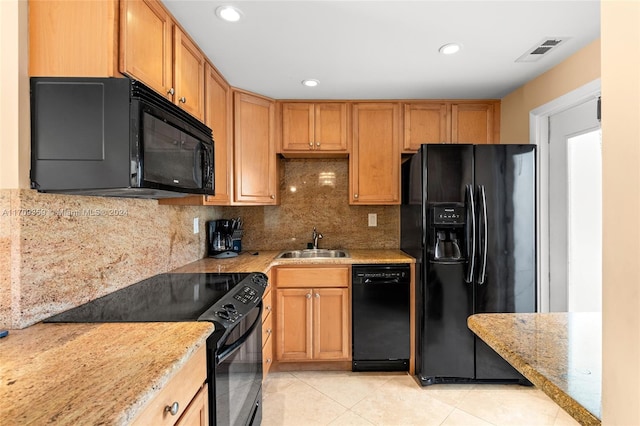 kitchen with light stone countertops, decorative backsplash, sink, and black appliances