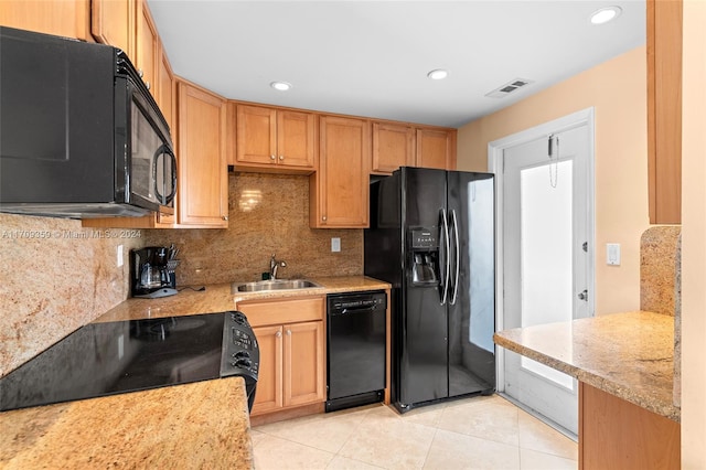 kitchen with black appliances, sink, tasteful backsplash, light tile patterned flooring, and light stone counters