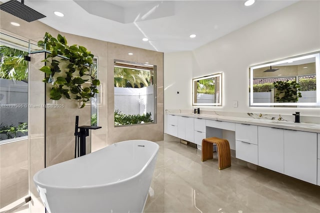 bathroom featuring vanity, plenty of natural light, a bath, and tile walls