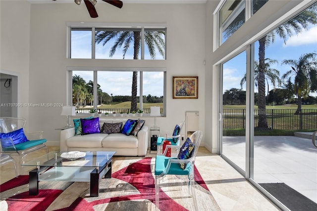 living room with ceiling fan, plenty of natural light, and a towering ceiling