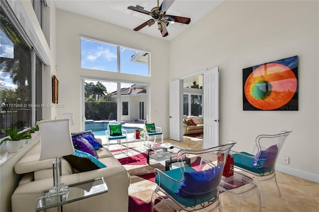 living room with ceiling fan and a towering ceiling