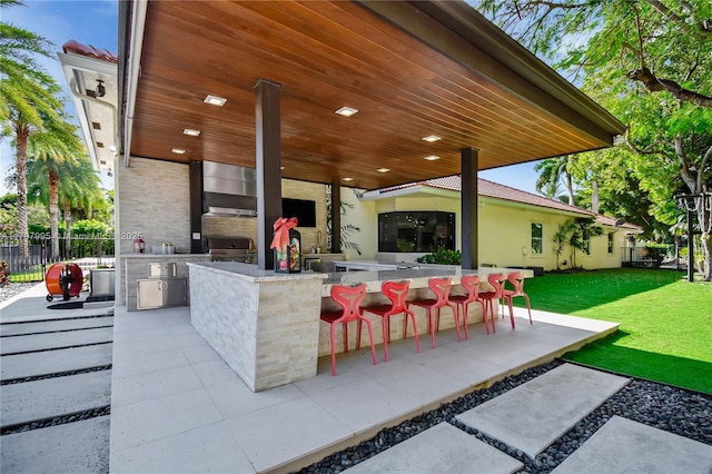 view of patio featuring exterior bar and an outdoor kitchen