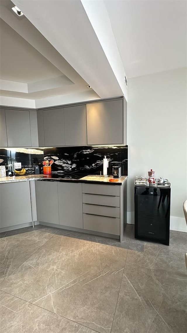 kitchen with decorative backsplash, a tray ceiling, and gray cabinetry