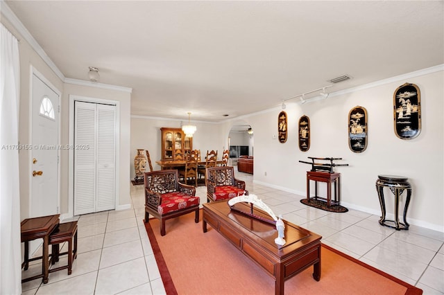 tiled living room with rail lighting, an inviting chandelier, and ornamental molding