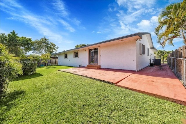 back of property with a yard, a patio, and central AC