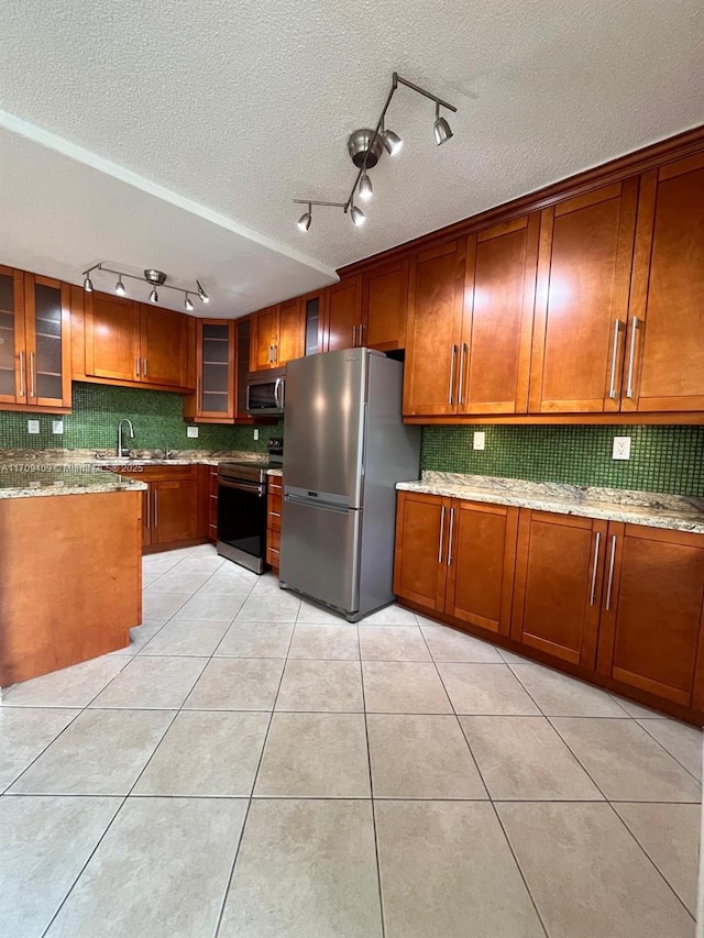 kitchen with light stone countertops, a textured ceiling, stainless steel appliances, sink, and light tile patterned flooring