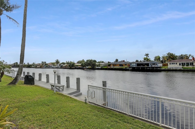 view of dock with a yard and a water view