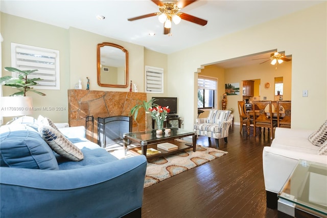 living room featuring dark hardwood / wood-style floors, ceiling fan, and a fireplace