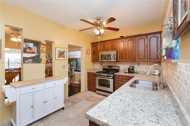 kitchen with appliances with stainless steel finishes, backsplash, ceiling fan, and sink