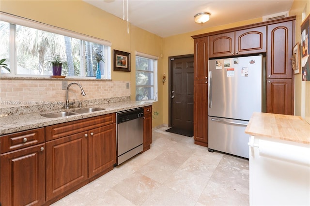 kitchen with decorative backsplash, sink, stainless steel appliances, and a wealth of natural light