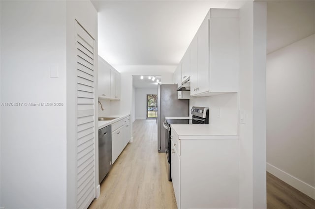 kitchen with light hardwood / wood-style floors, white cabinetry, sink, and appliances with stainless steel finishes