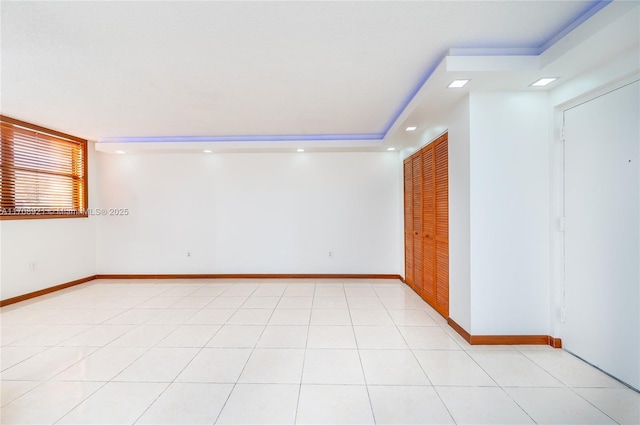 empty room featuring light tile patterned floors and a tray ceiling