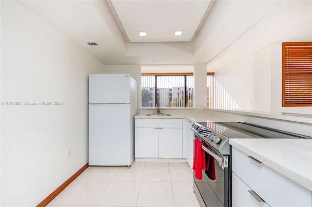 kitchen featuring sink, electric stove, light tile patterned floors, white refrigerator, and white cabinetry