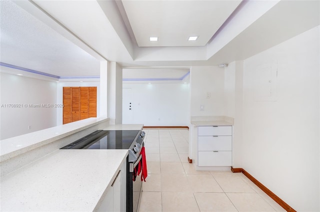 kitchen featuring light stone counters, stainless steel range, white cabinets, and light tile patterned floors