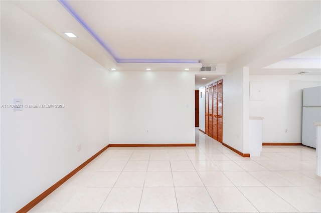 spare room with a tray ceiling and light tile patterned flooring