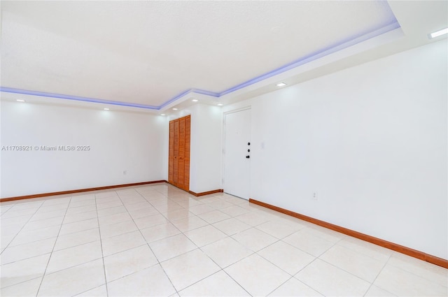 tiled spare room with a tray ceiling