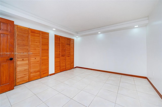 unfurnished bedroom featuring light tile patterned floors and two closets