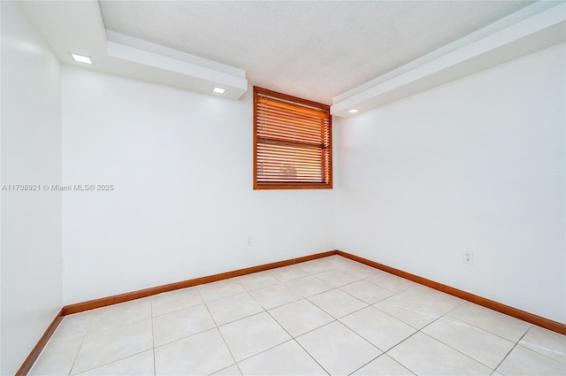 spare room featuring a raised ceiling and light tile patterned floors