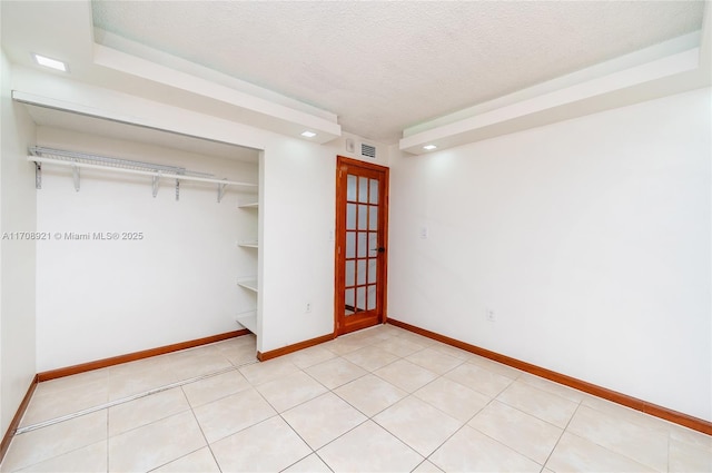 unfurnished bedroom with a textured ceiling, a closet, and light tile patterned flooring