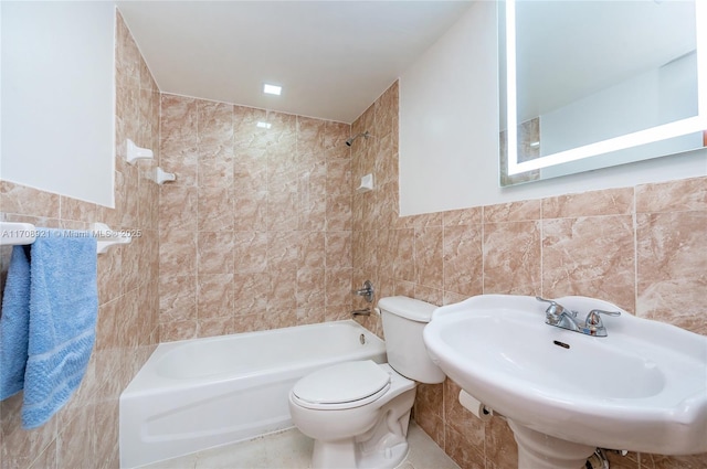 full bathroom featuring tile patterned floors, tiled shower / bath combo, sink, tile walls, and toilet