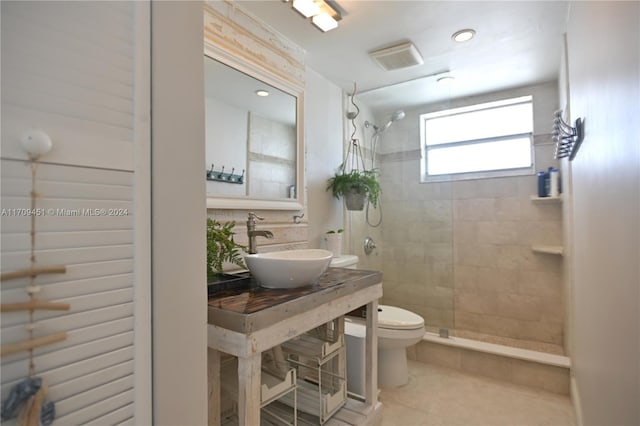 bathroom featuring tile patterned floors, sink, tiled shower, and toilet