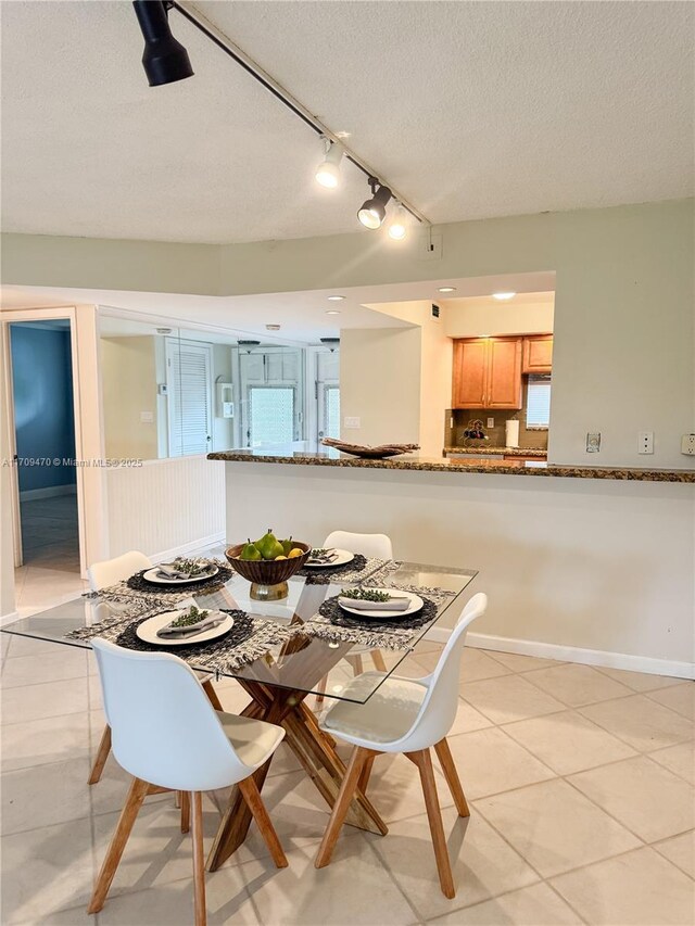 dining space with light tile patterned floors, baseboards, and a textured ceiling