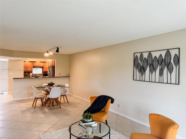 interior space with rail lighting, light tile patterned floors, baseboards, and a textured ceiling