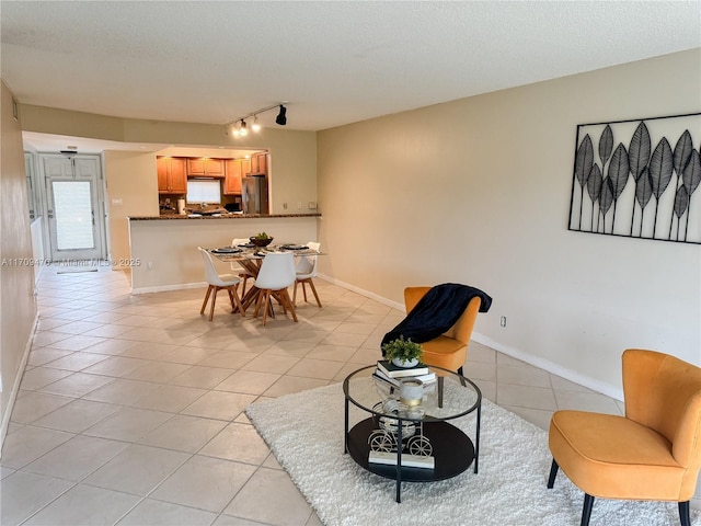 living room featuring light tile patterned floors, baseboards, a textured ceiling, and track lighting