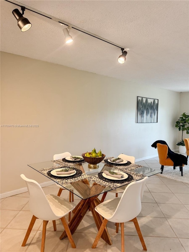 dining space featuring light tile patterned floors, baseboards, and a textured ceiling