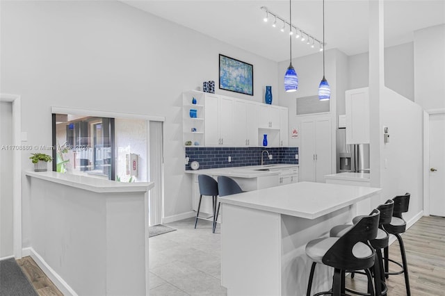 kitchen with pendant lighting, a breakfast bar, white cabinets, kitchen peninsula, and stainless steel fridge with ice dispenser