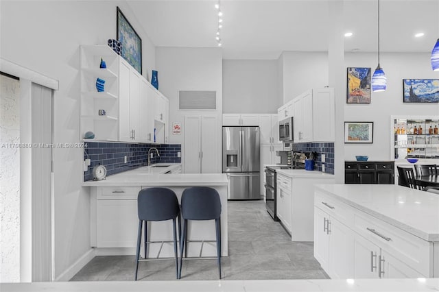 kitchen featuring white cabinetry, sink, decorative light fixtures, and appliances with stainless steel finishes