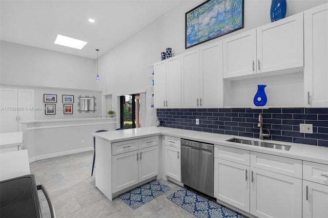 kitchen featuring kitchen peninsula, a skylight, stainless steel dishwasher, sink, and white cabinets