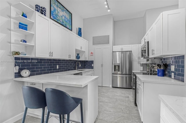 kitchen featuring white cabinets, appliances with stainless steel finishes, light stone counters, and a kitchen breakfast bar