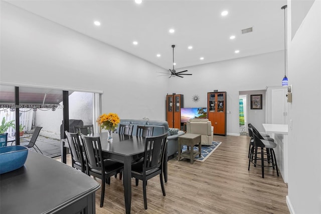 dining area with ceiling fan, a high ceiling, and light wood-type flooring