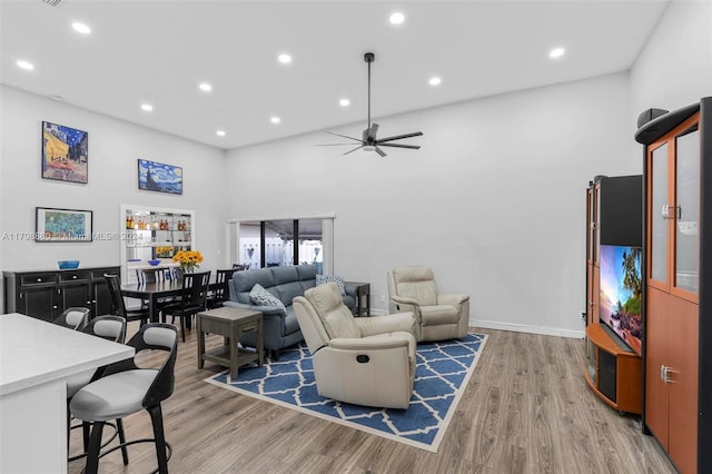 living room featuring ceiling fan, a towering ceiling, and hardwood / wood-style flooring