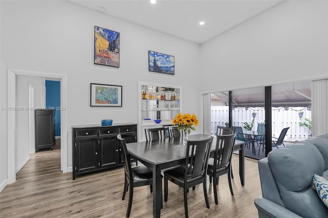 dining space with a high ceiling and light hardwood / wood-style flooring