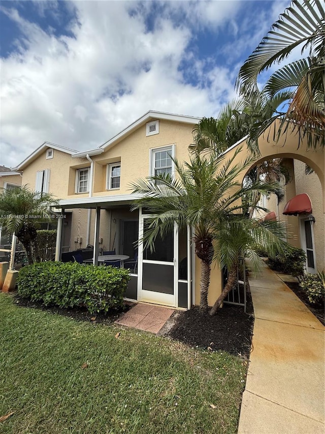 rear view of house with a sunroom and a yard