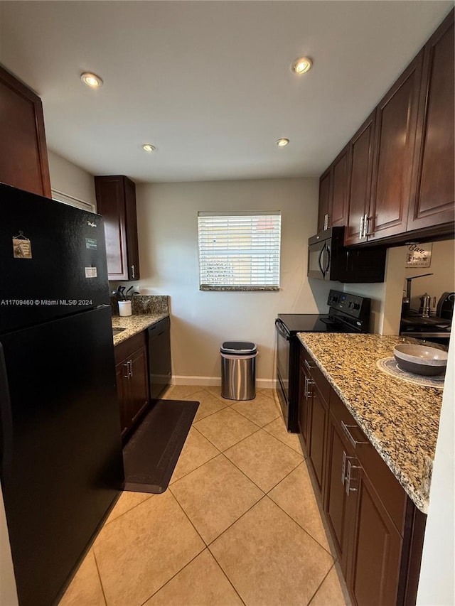 kitchen featuring light tile patterned floors, light stone counters, dark brown cabinets, and black appliances