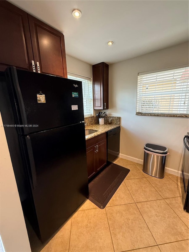 kitchen with dark brown cabinetry, light tile patterned flooring, and black appliances