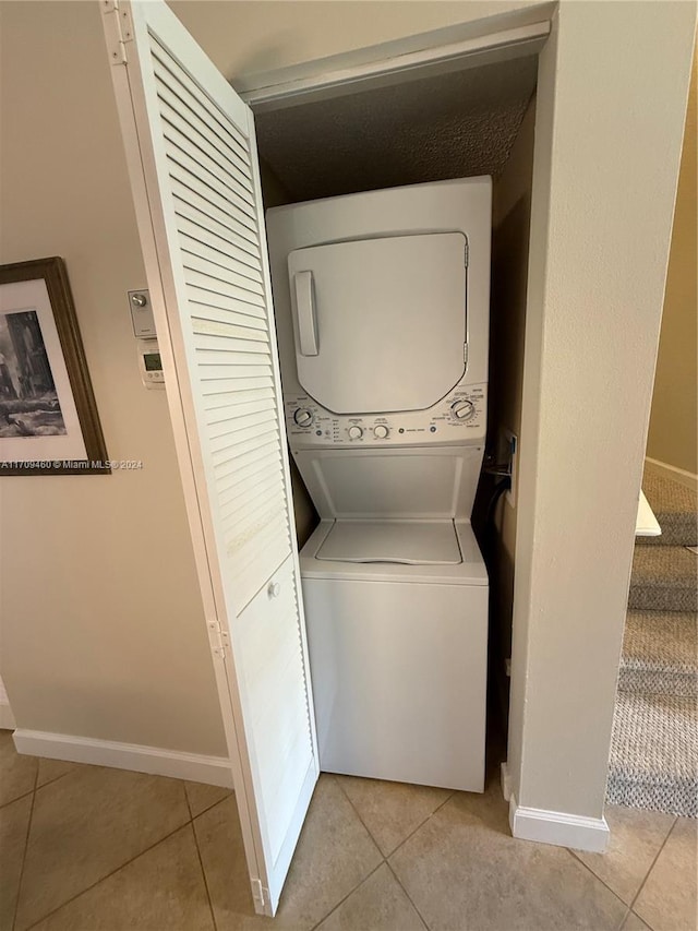 laundry room featuring stacked washer and dryer and light tile patterned floors