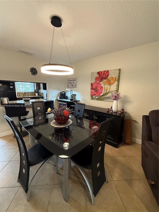 dining area featuring light tile patterned floors and a textured ceiling