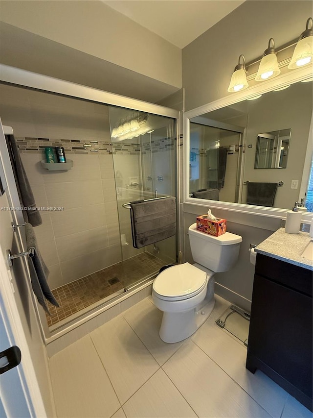 bathroom featuring tile patterned flooring, vanity, toilet, and a shower with shower door